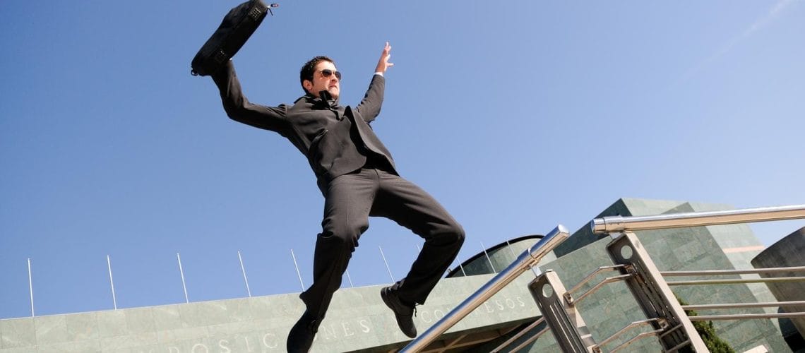 Young handsome businessman jumping in the street